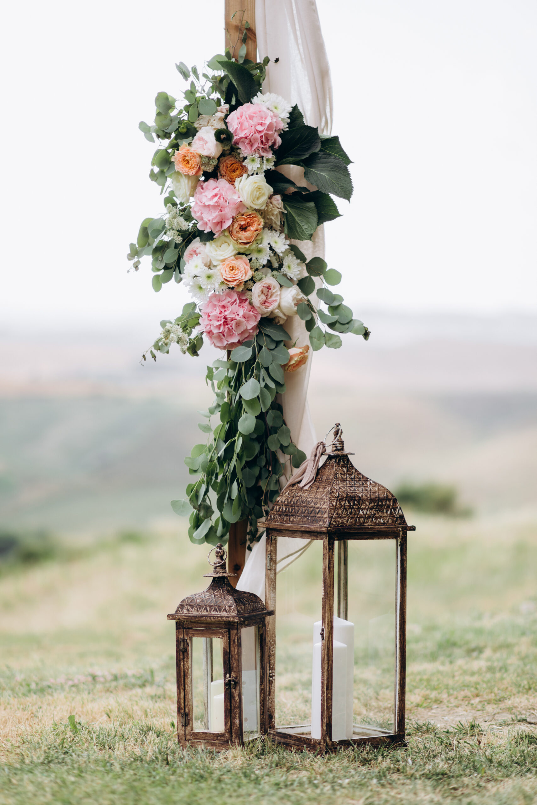 Floral composition made of eucalyptus and tender pink flowers and candles outdoors